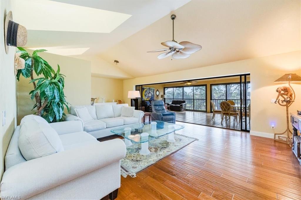 a living room with furniture large window and wooden floor