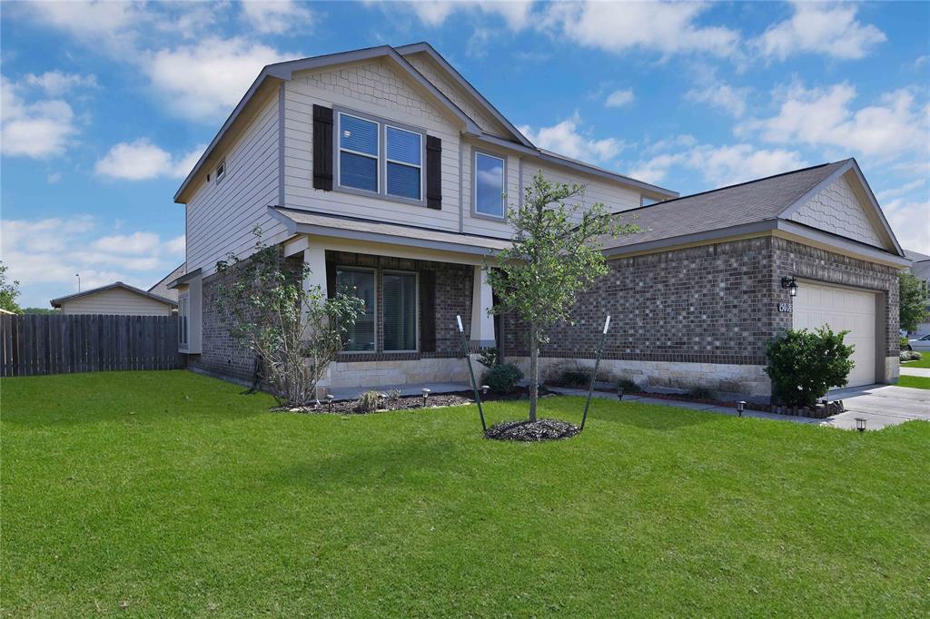 This is a modern two-story home featuring a combination of brick and siding exterior, a two-car garage, and low maintenance lawn. It has a welcoming entrance with small trees planted in the front yard, offering potential for landscaping enhancements.