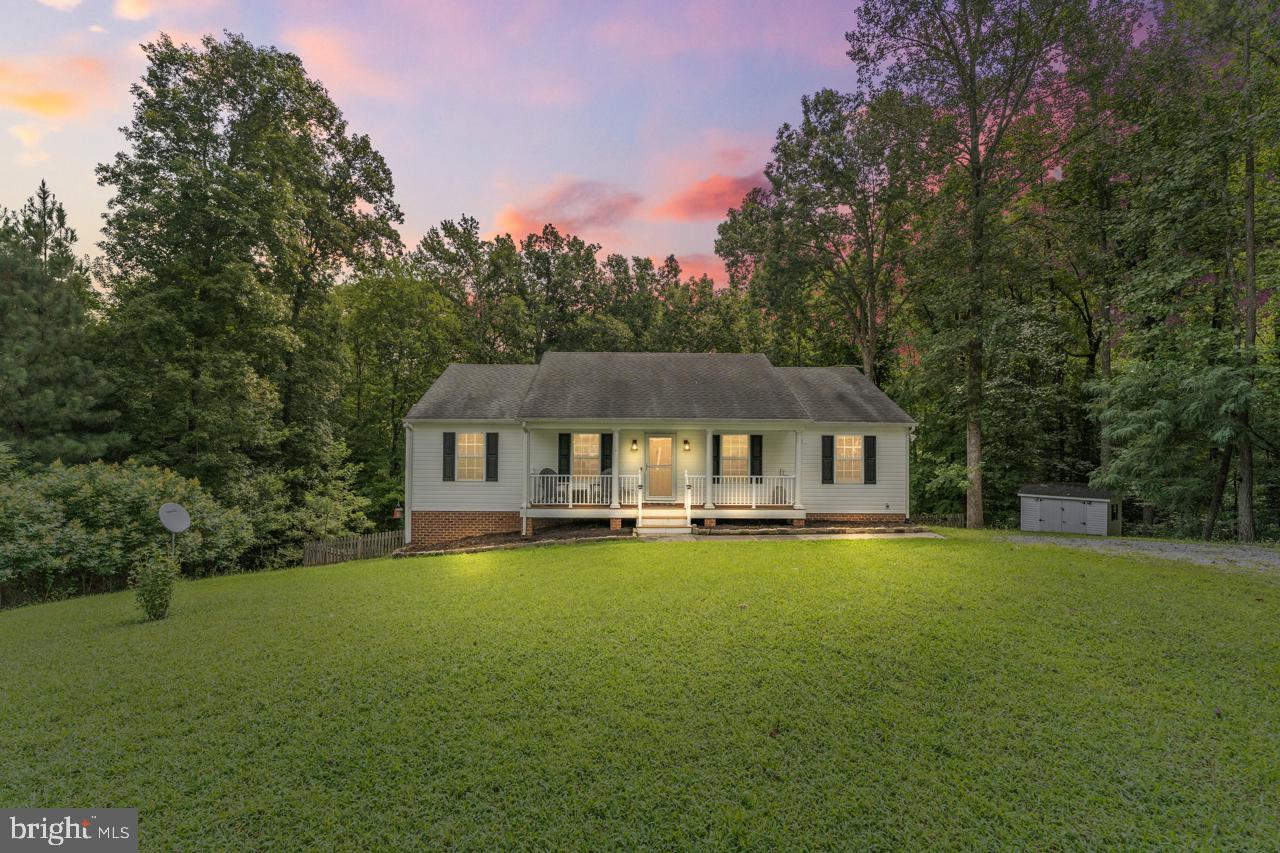 a house that is sitting in the grass with large trees