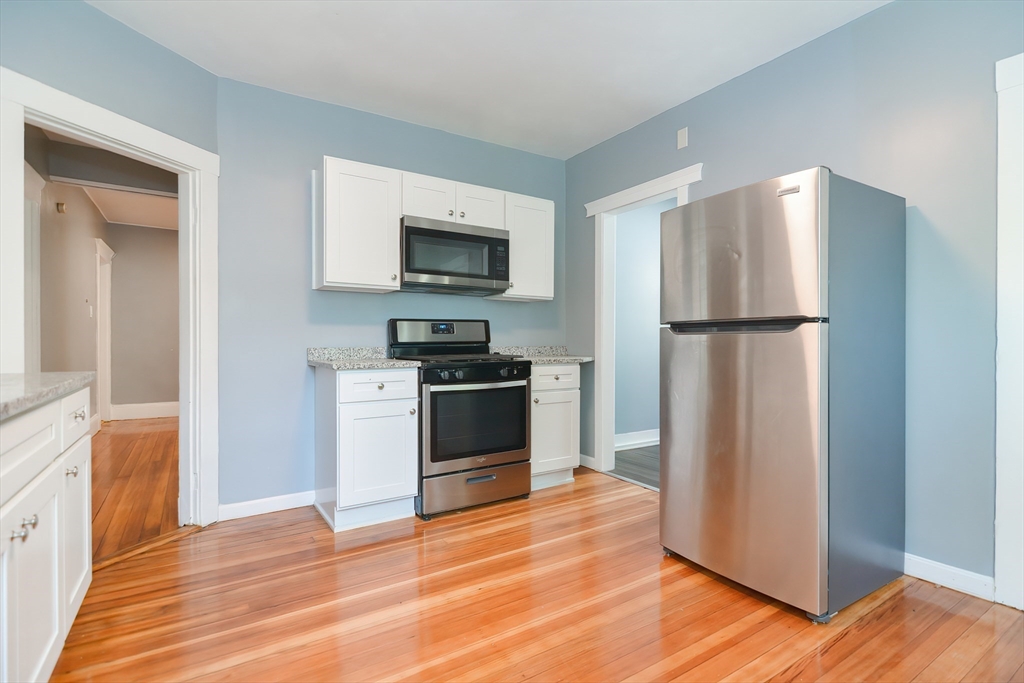 a kitchen with a refrigerator a stove top oven and wooden floor