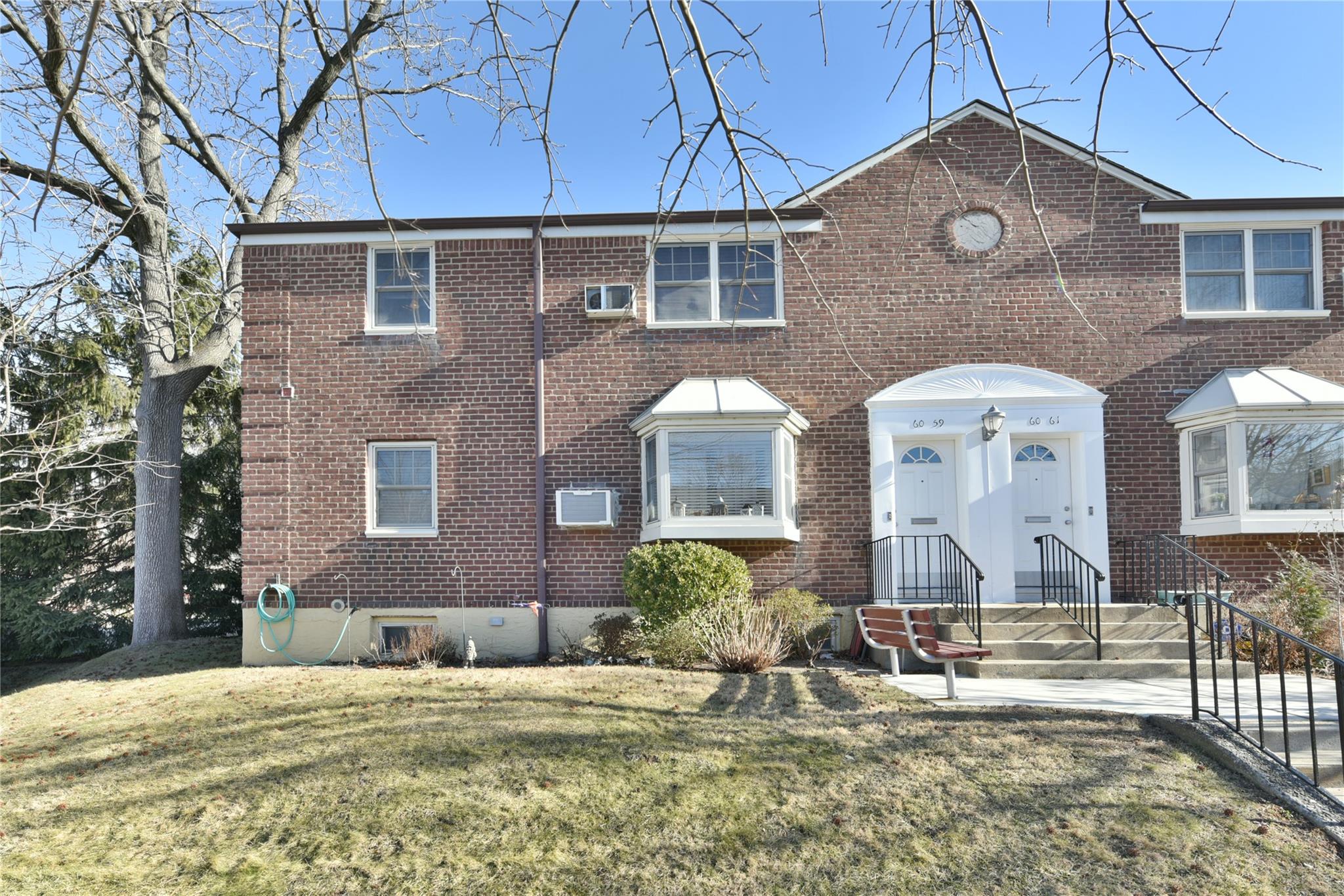 View of front of home with an AC wall unit and a front yard