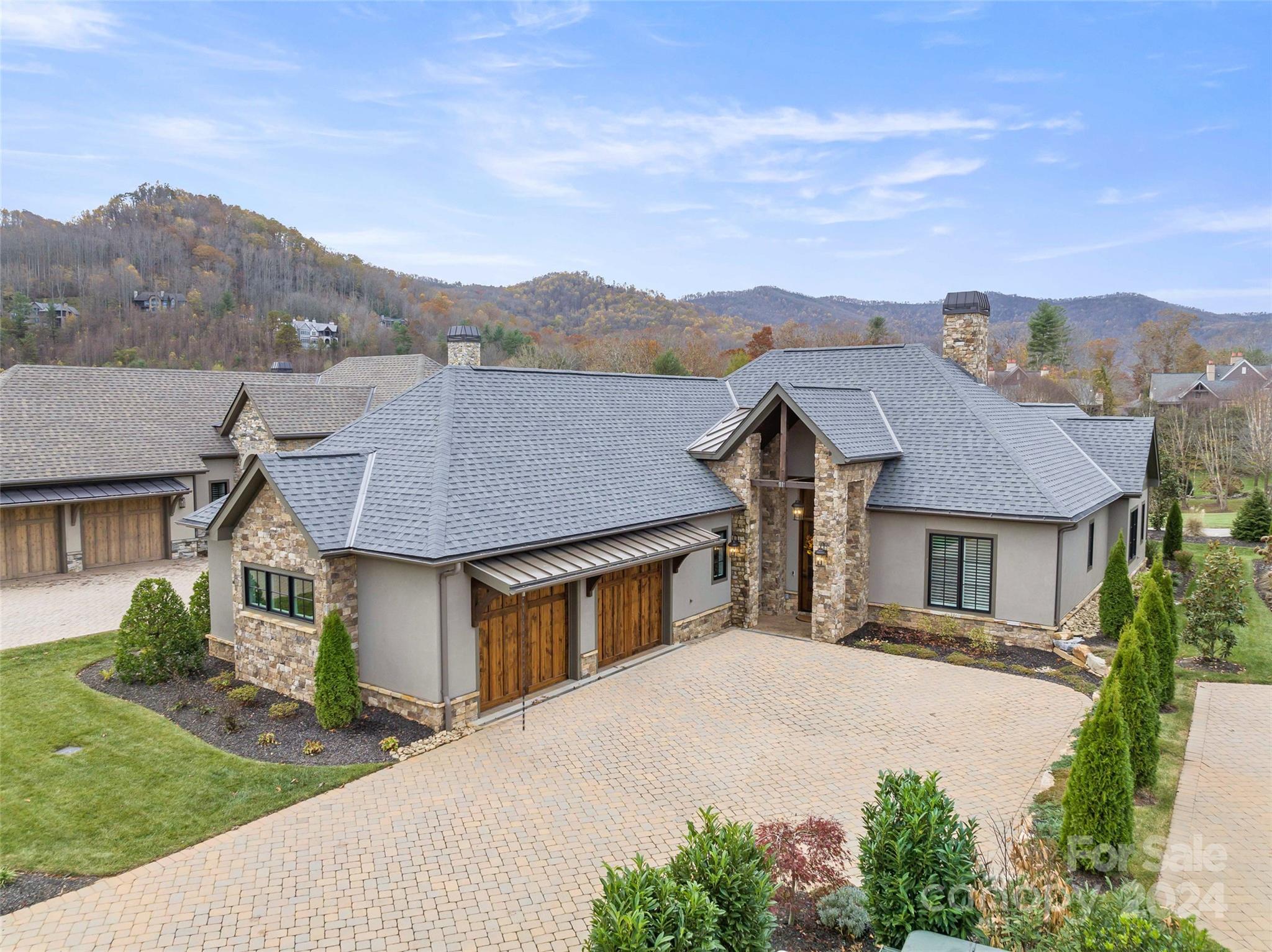 a front view of a house with a yard and mountain view in back