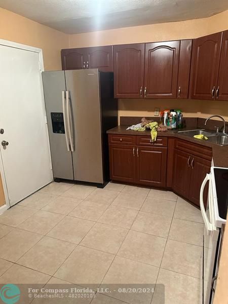 a kitchen with granite countertop a refrigerator and a stove top oven