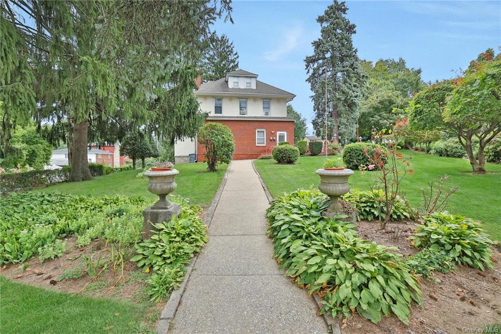 a view of a brick house with a big yard and potted plants