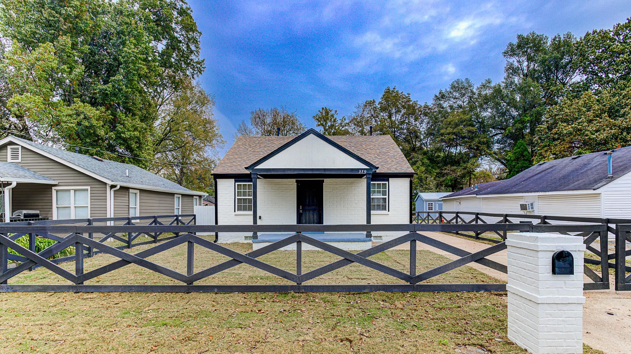 a front view of a house with wooden fence and a bench