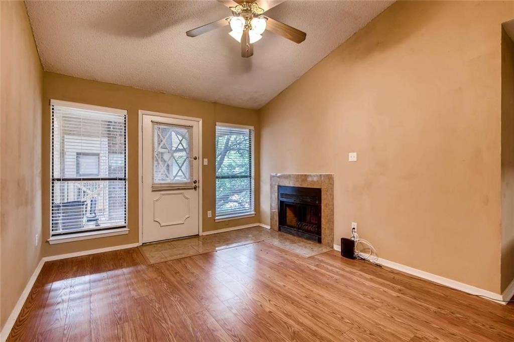 an empty room with windows fireplace and wooden floor