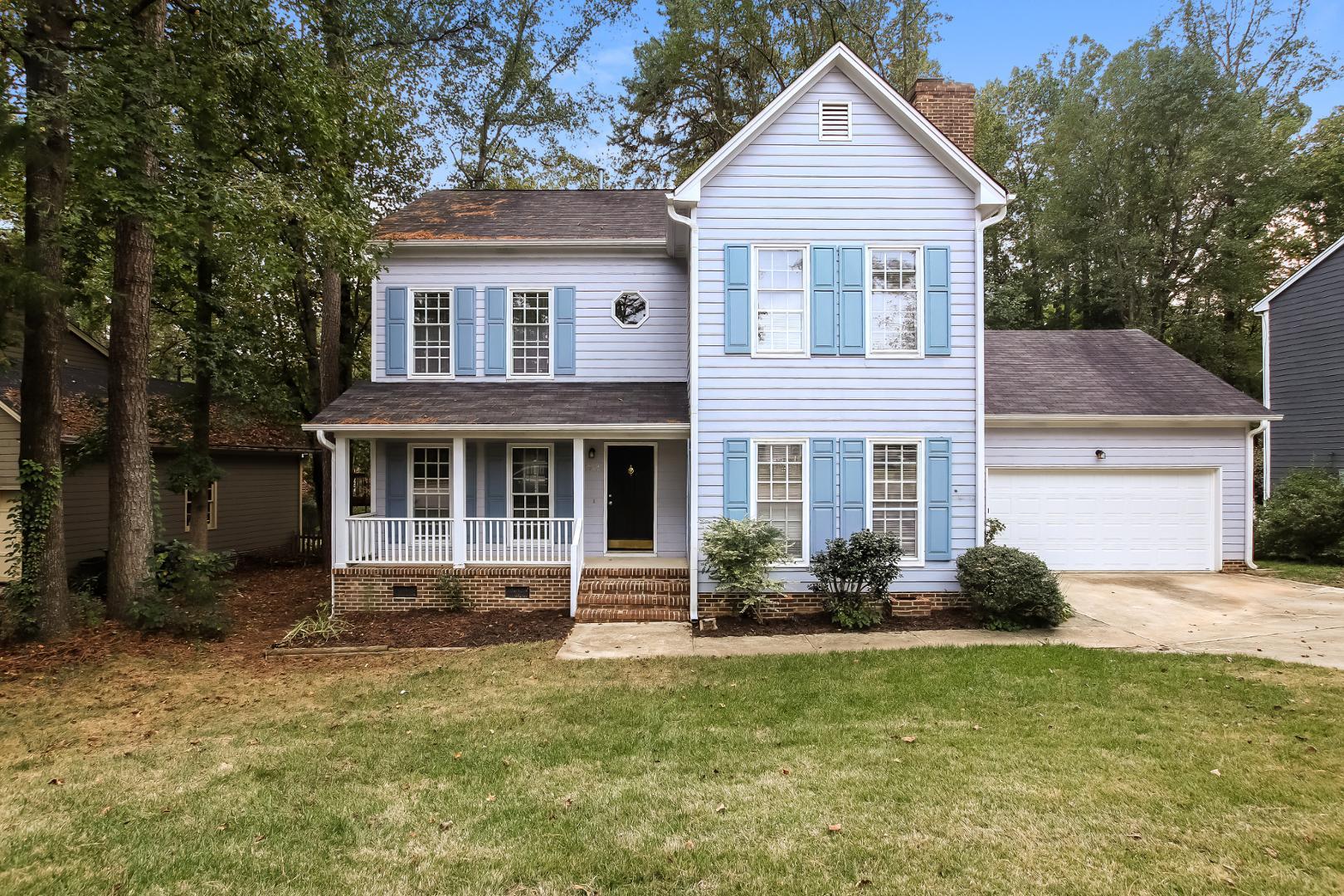 a front view of a house with a yard and trees