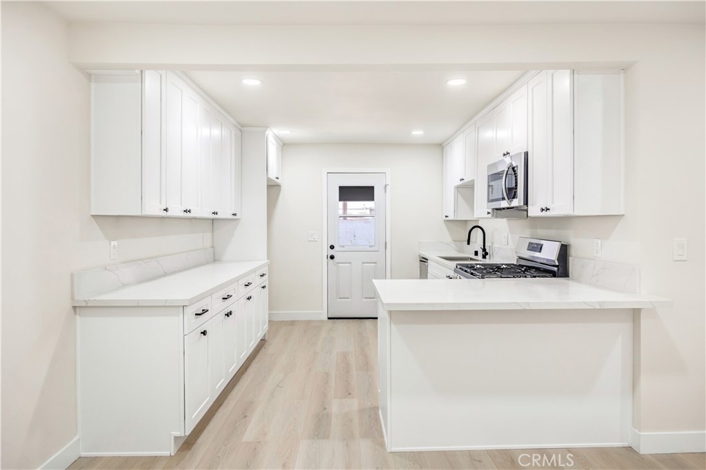 a kitchen with granite countertop a sink stainless steel appliances and white cabinets