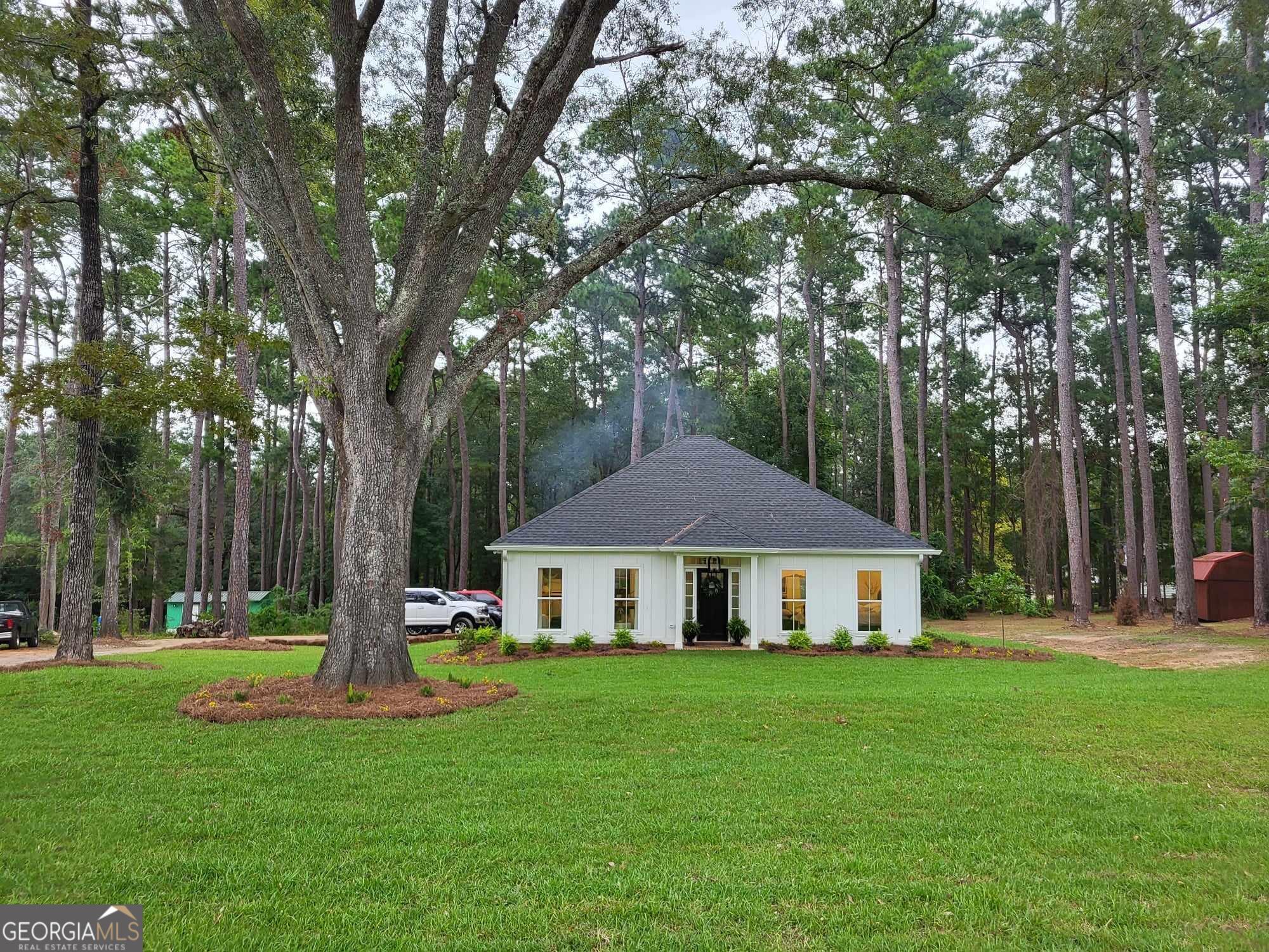 a front view of a house with garden and trees