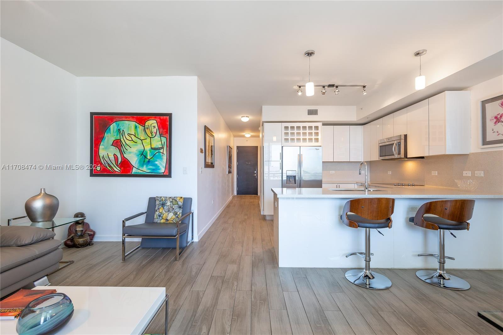 a living room with kitchen island stainless steel appliances furniture and wooden floor