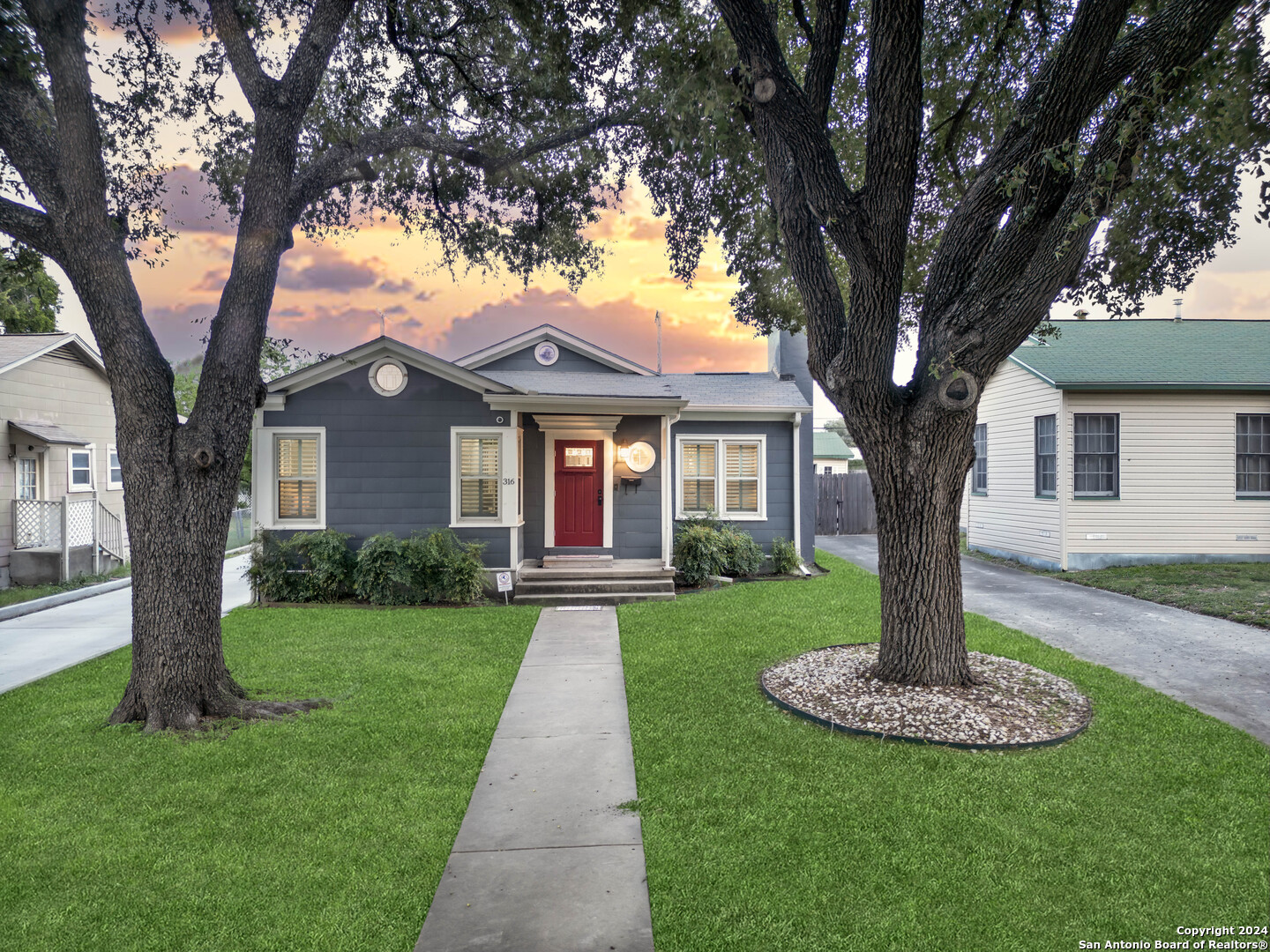 a front view of a house with yard and tree