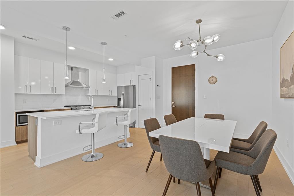 a kitchen with a dining table chairs cabinets and stainless steel appliances