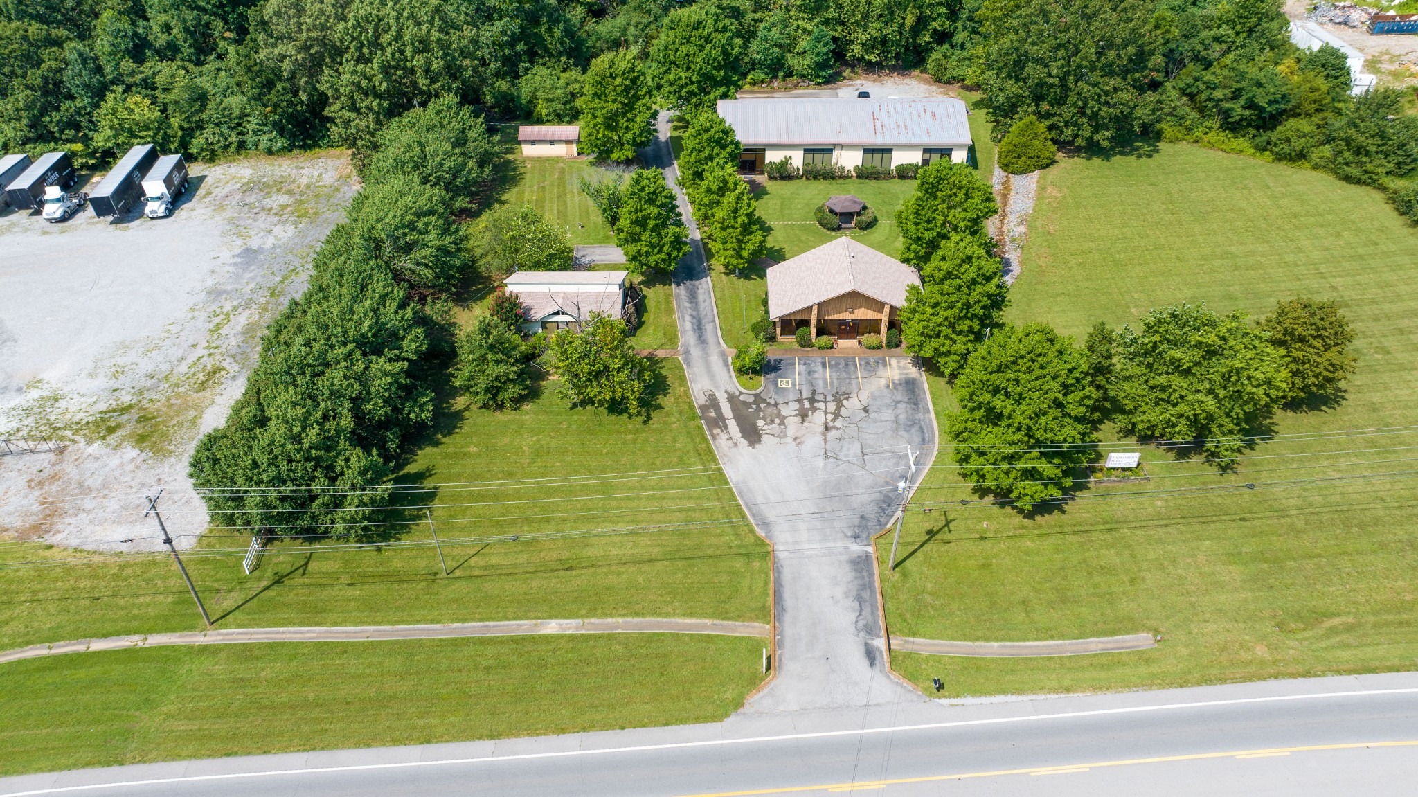 an aerial view of a residential houses with outdoor space and trees all around