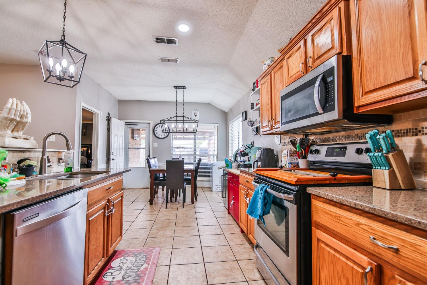 a kitchen with stainless steel appliances granite countertop a stove a sink dishwasher and cabinets with wooden floor