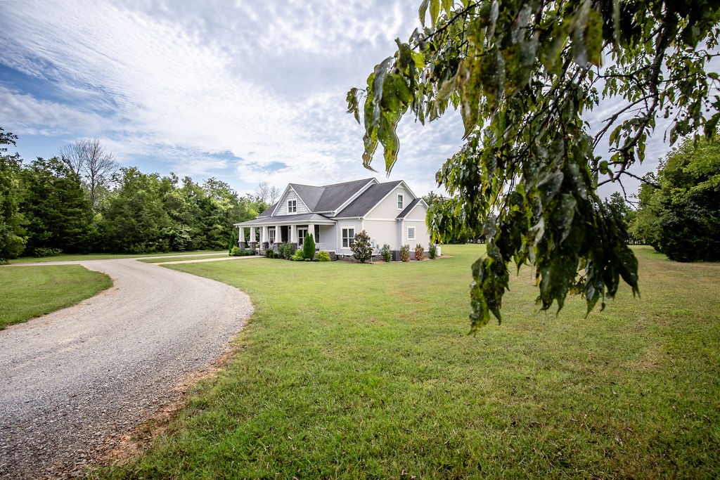 a view of house with garden space and trees in the background