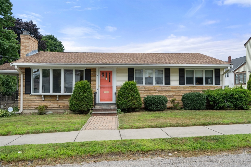 a front view of a house with a yard and plants