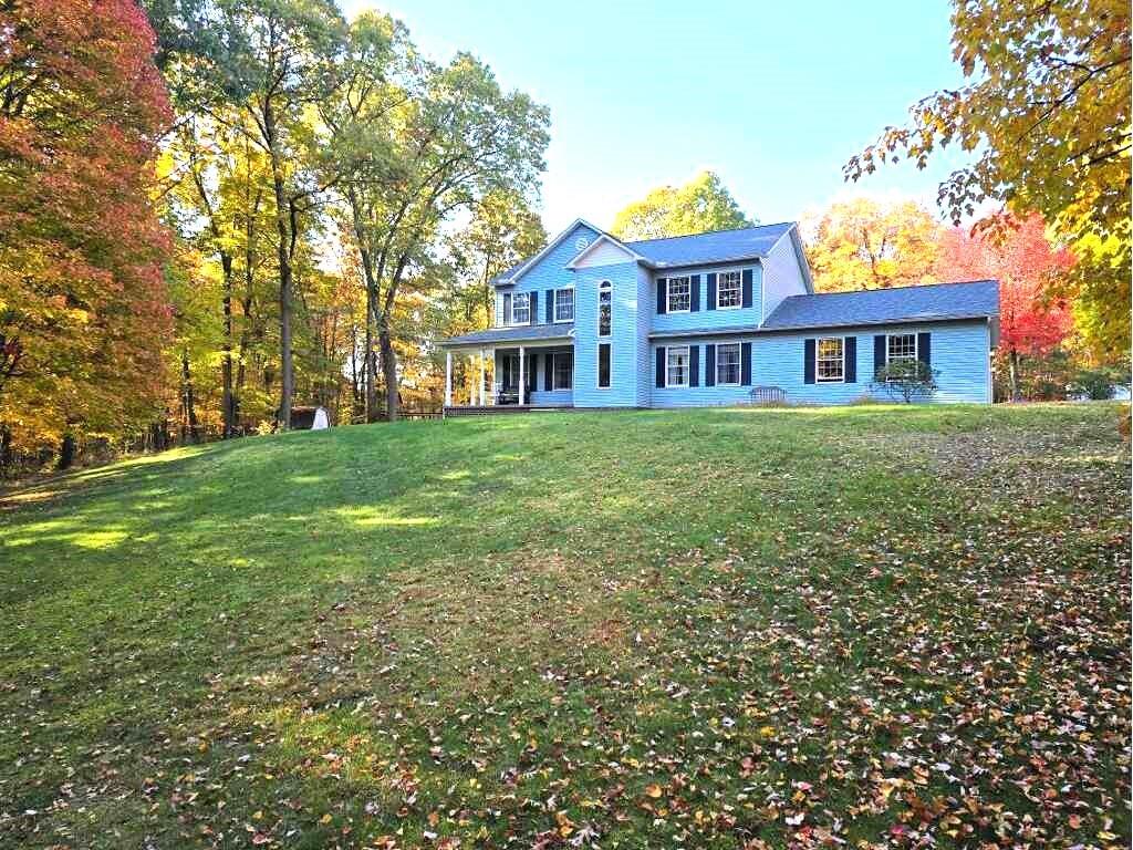 a view of a house with a big yard and large trees