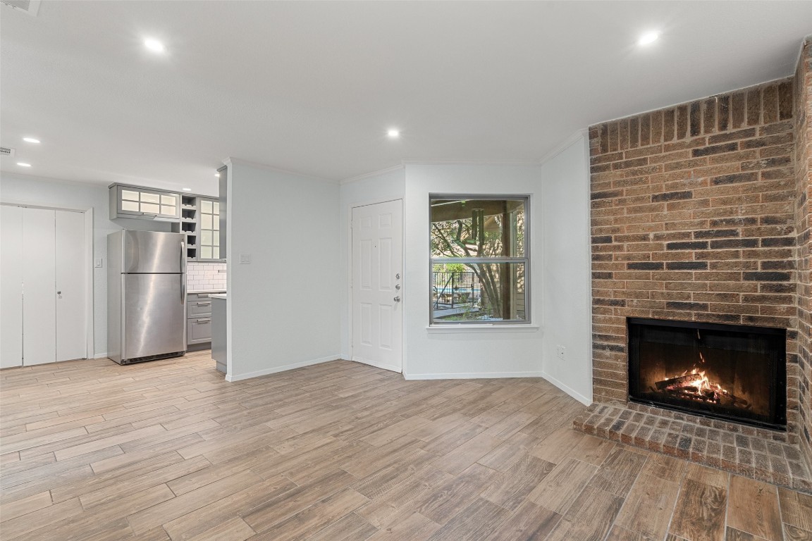 a view of empty room with kitchen and fireplace