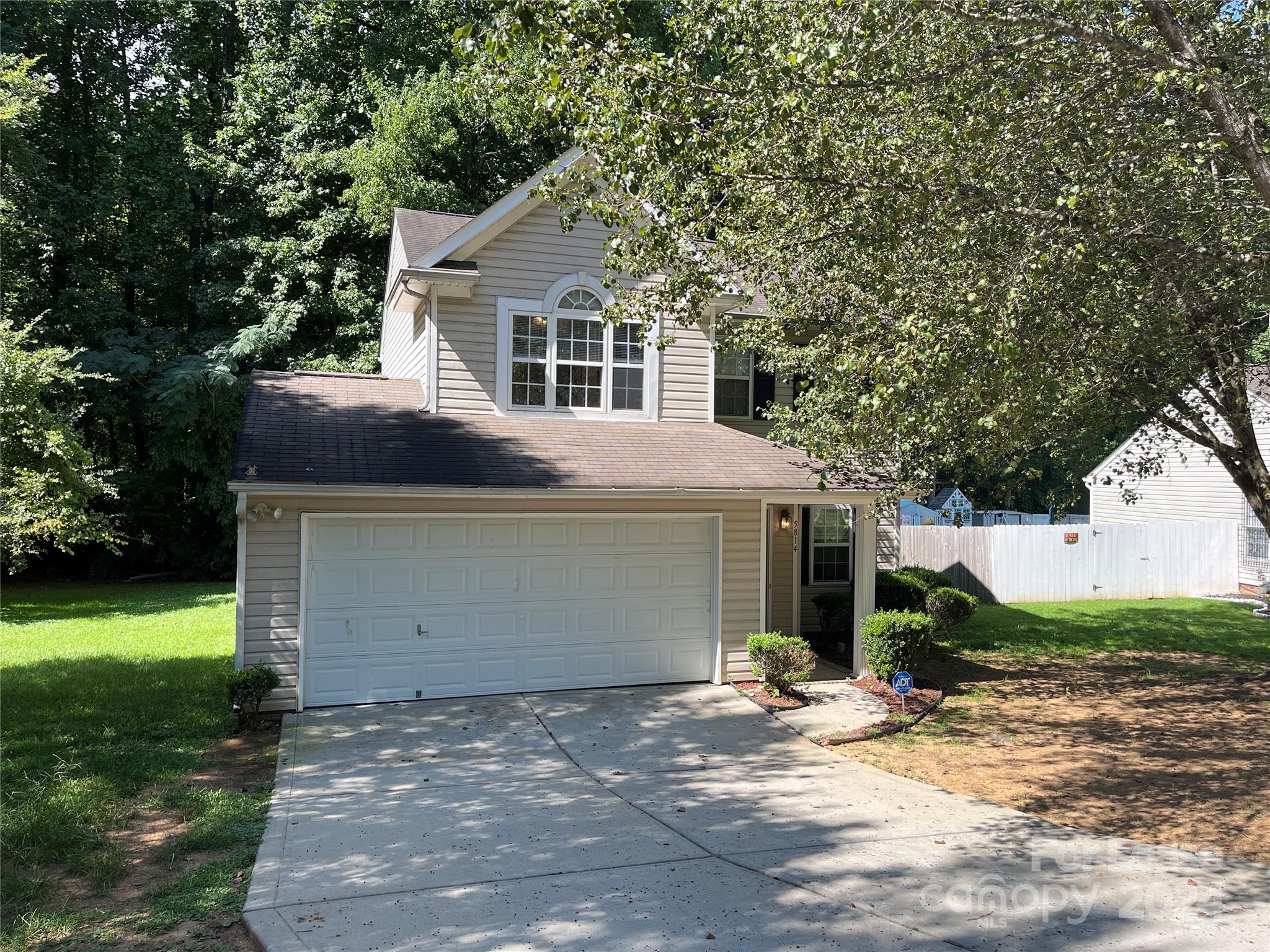 a view of a house with a yard and large tree