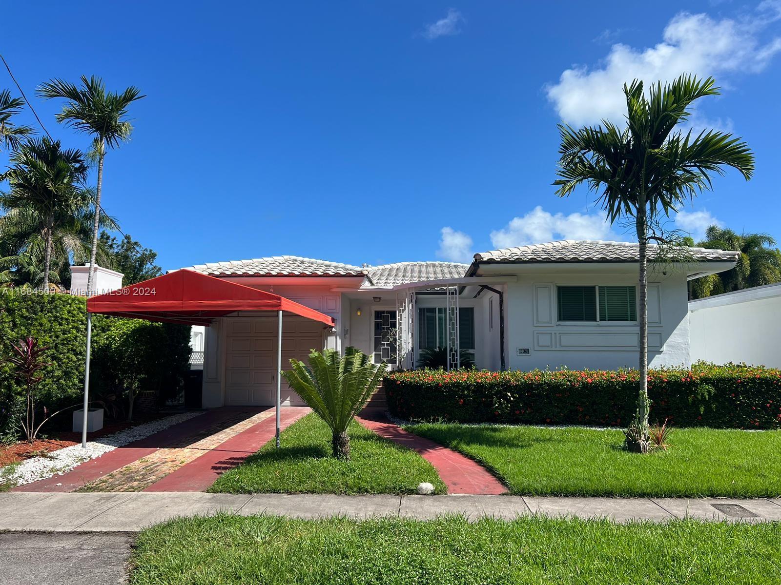 a front view of a house with a yard and potted plants