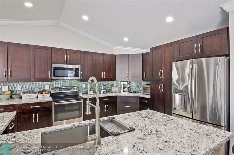 a kitchen with stainless steel appliances kitchen island granite countertop a refrigerator stove and sink