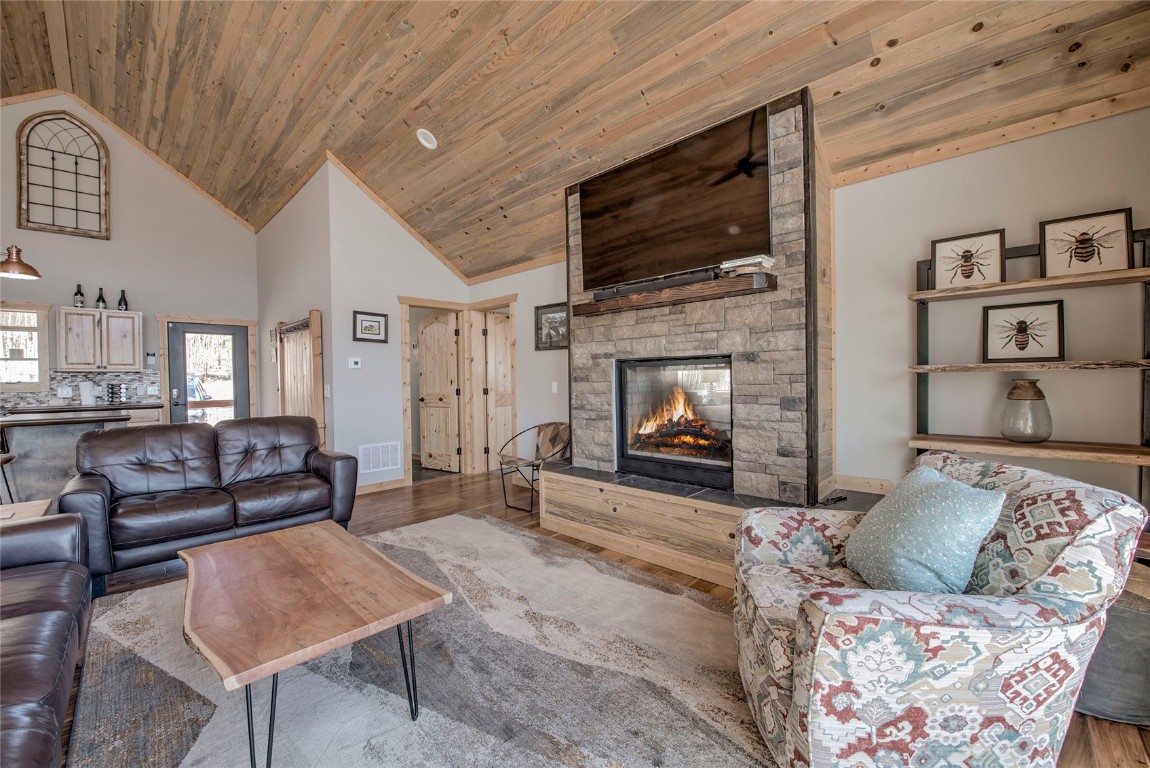 Living room with high vaulted ceiling, a fireplace, wood ceiling, and wood-type flooring