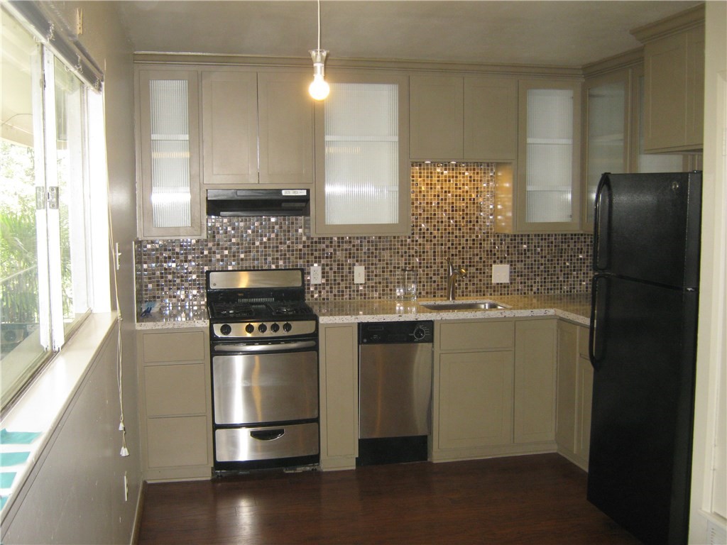 a kitchen with granite countertop a refrigerator stove and sink