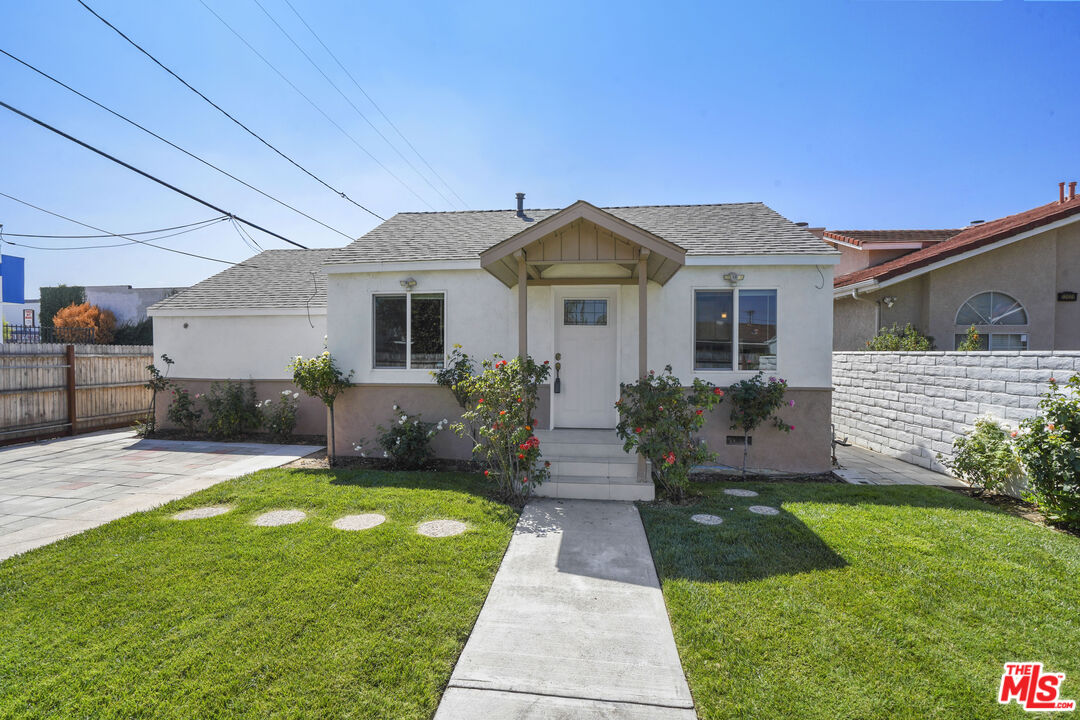 a front view of a house with a yard and potted plants