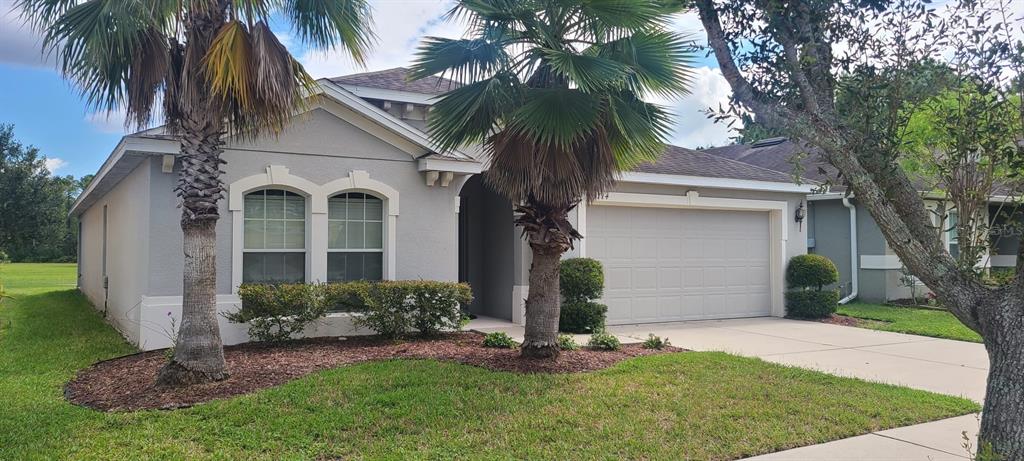 a front view of a house with a garden and palm trees