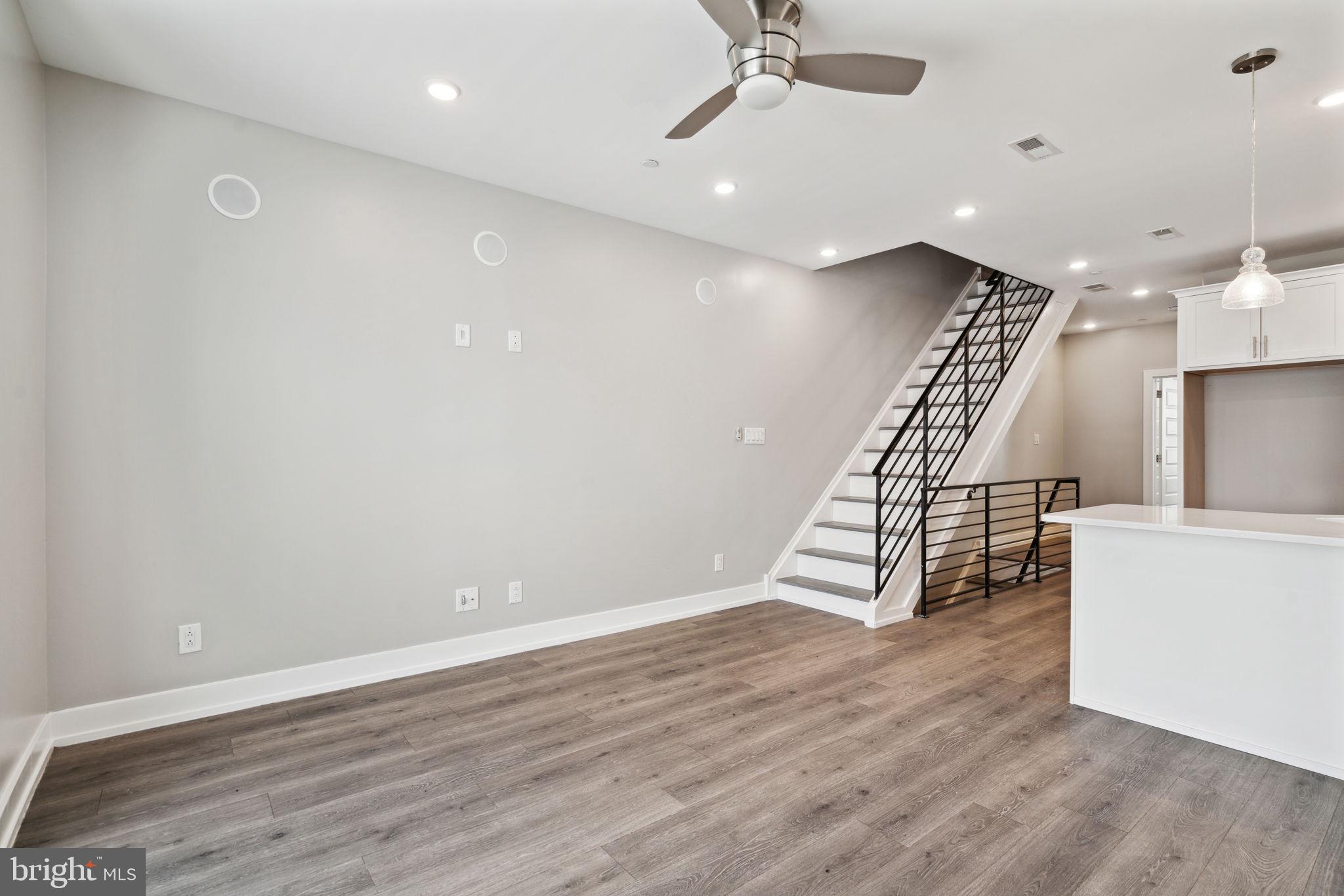 an empty room with wooden floor staircase and a ceiling fan