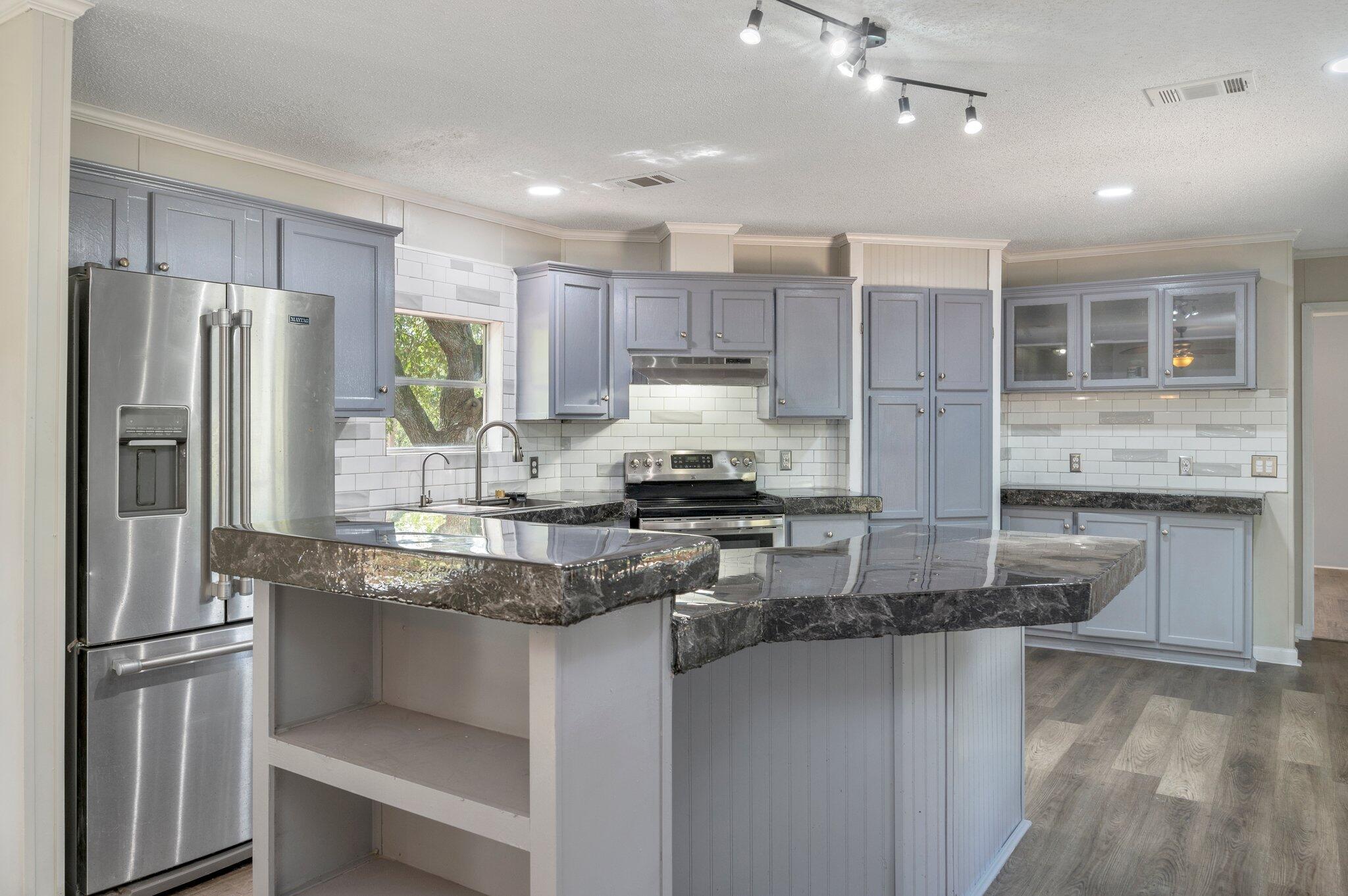 a kitchen with stainless steel appliances granite countertop a refrigerator and a stove