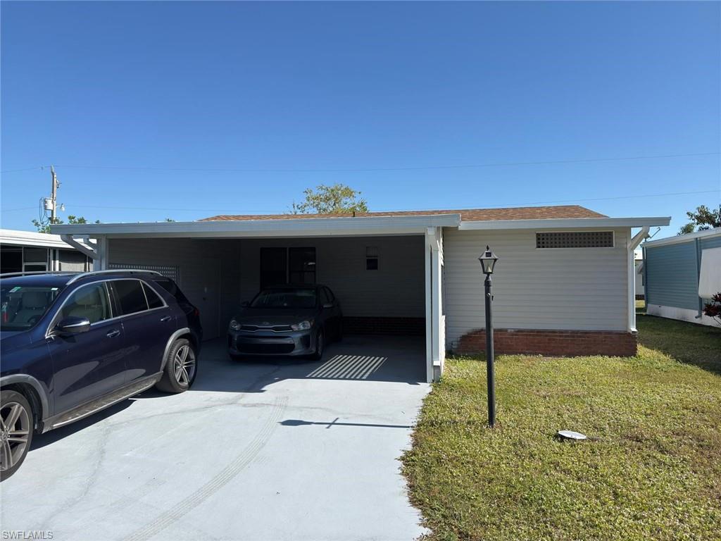 Single story home featuring a front lawn and a carport