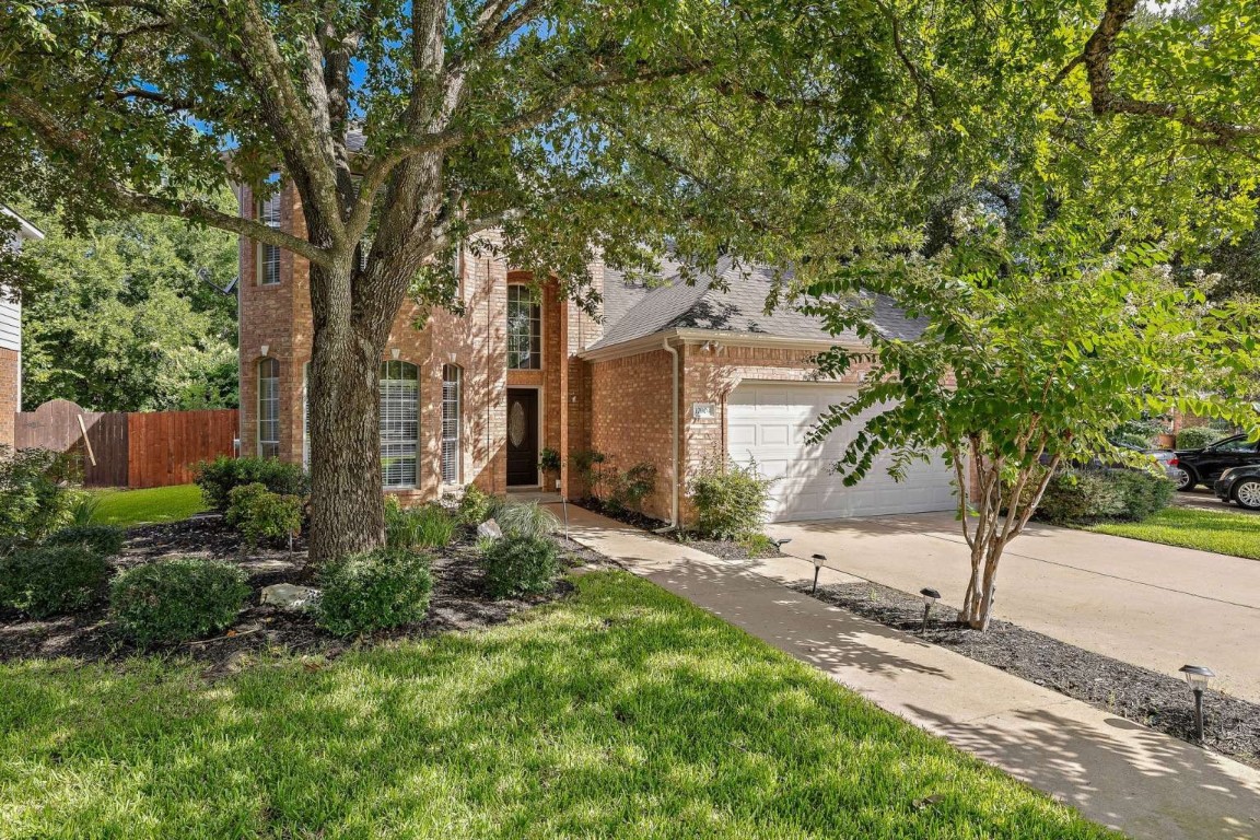 a front view of a house with a yard and tree s