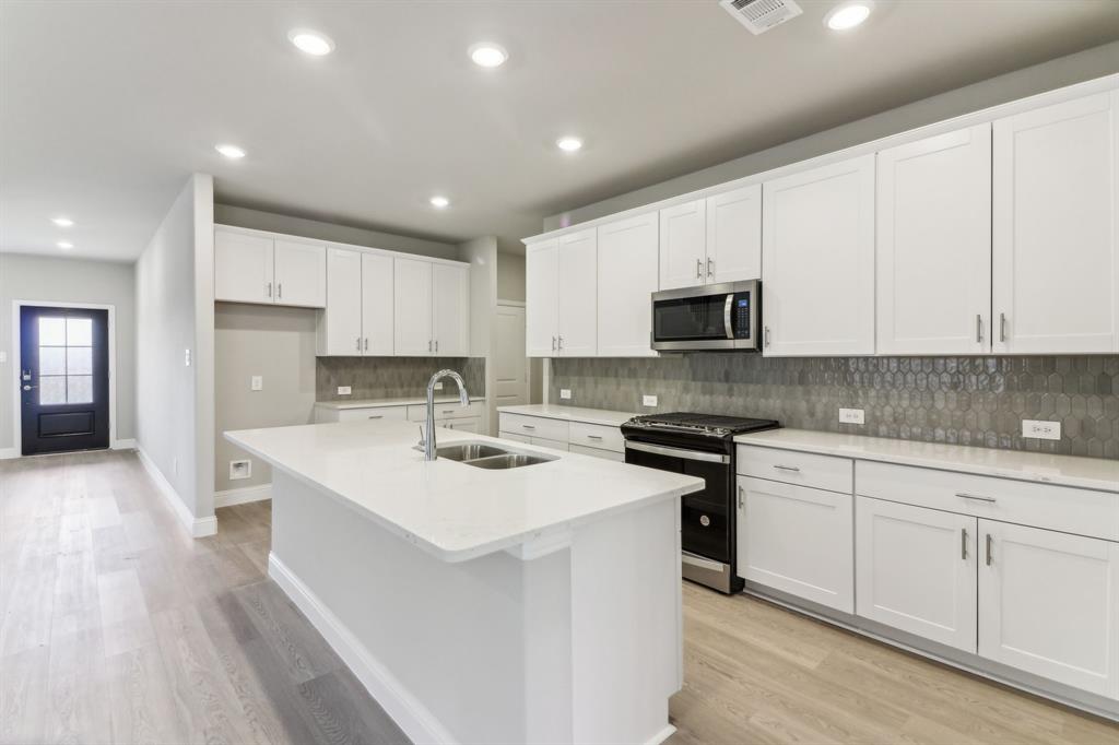 a kitchen with a sink stove cabinets and refrigerator