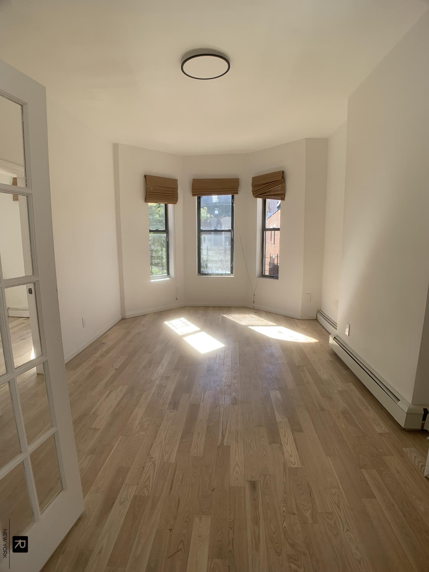 an empty room with wooden floor and windows