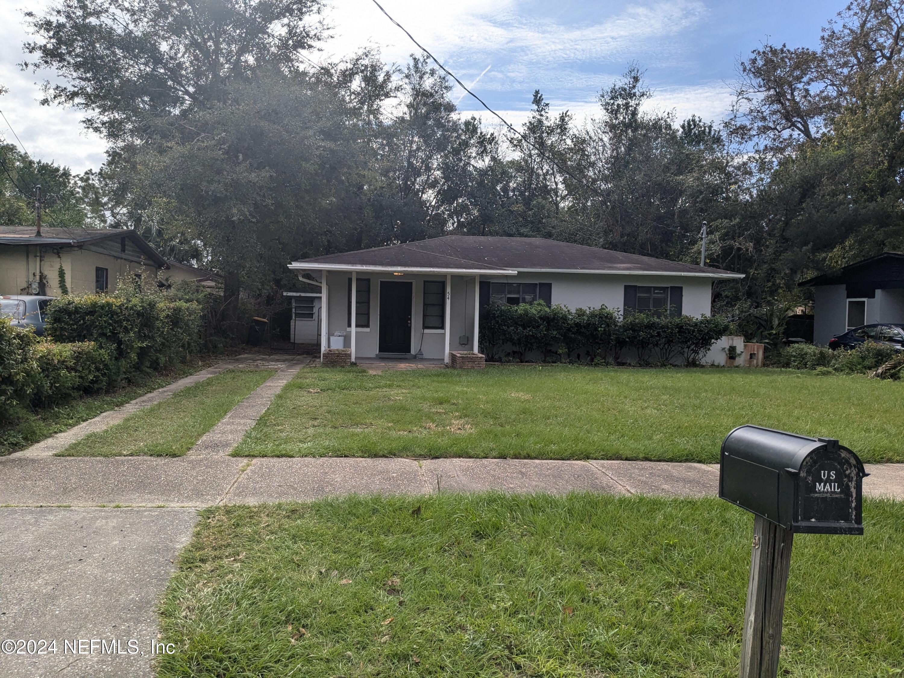 a front view of a house with a yard and trees