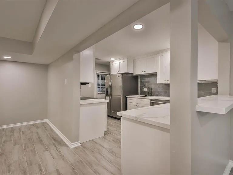 a kitchen with a refrigerator a stove top oven and white cabinets