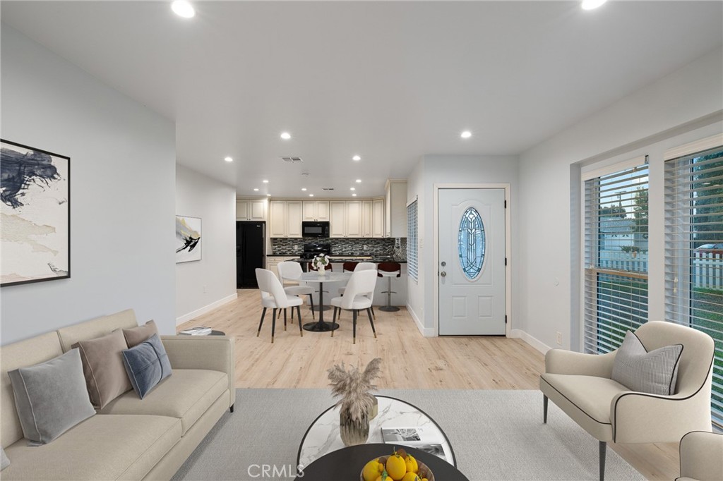 a living room with furniture kitchen view and a large window