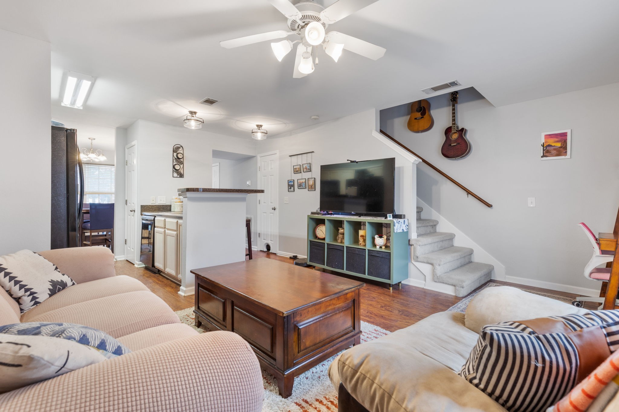 a living room with furniture a flat screen tv and kitchen view