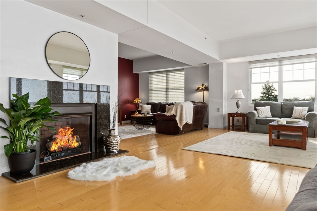 a living room with furniture a fireplace a potted plant and a large window