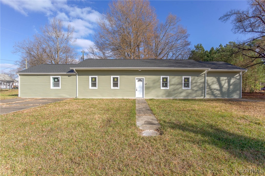 front view of house with yard and trees in the background