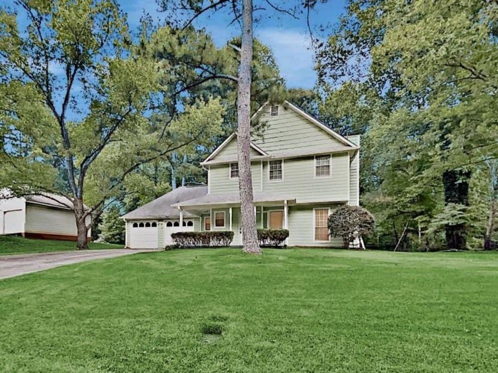 a front view of a house with a yard tree and green space