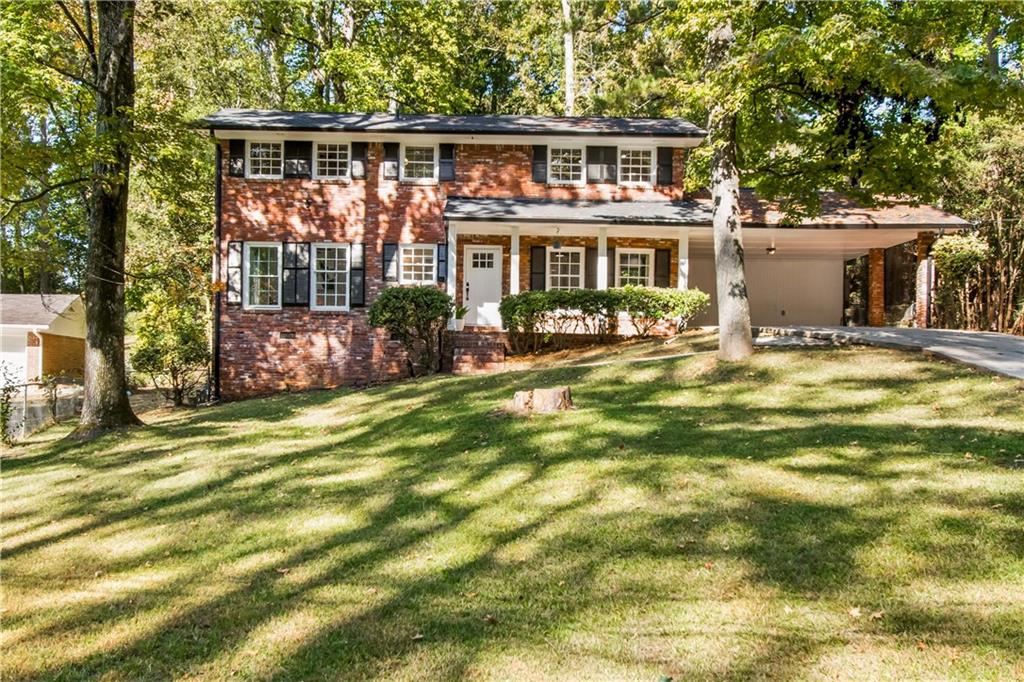 a front view of house with outdoor seating and covered with trees