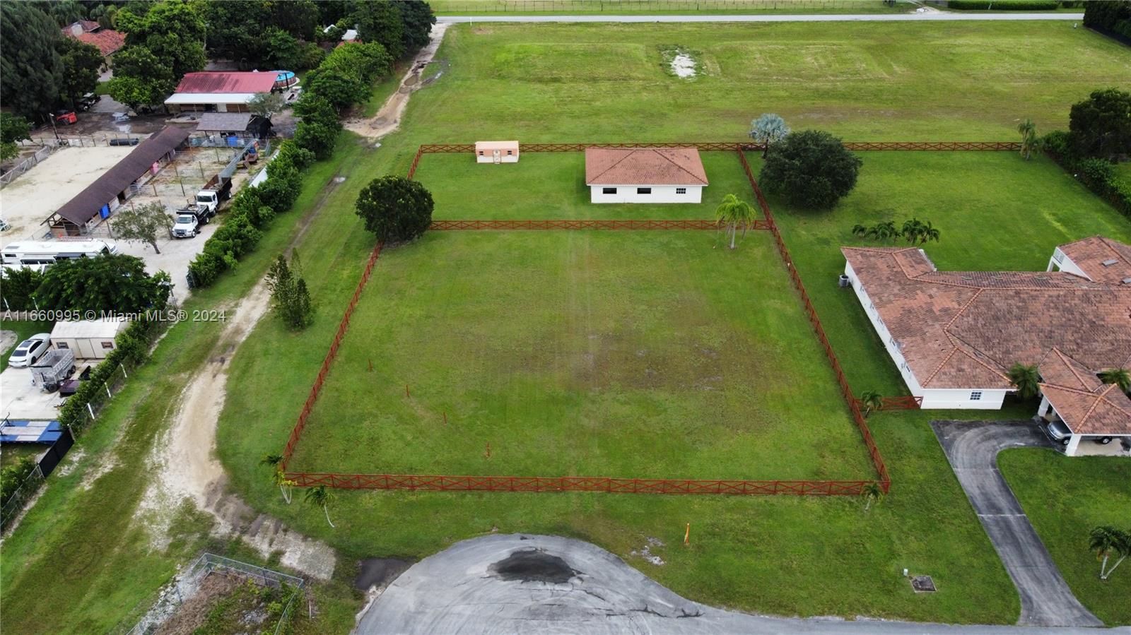 an aerial view of a residential houses with outdoor space and trees