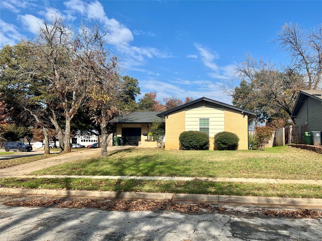 a view of a house with a yard and large tree