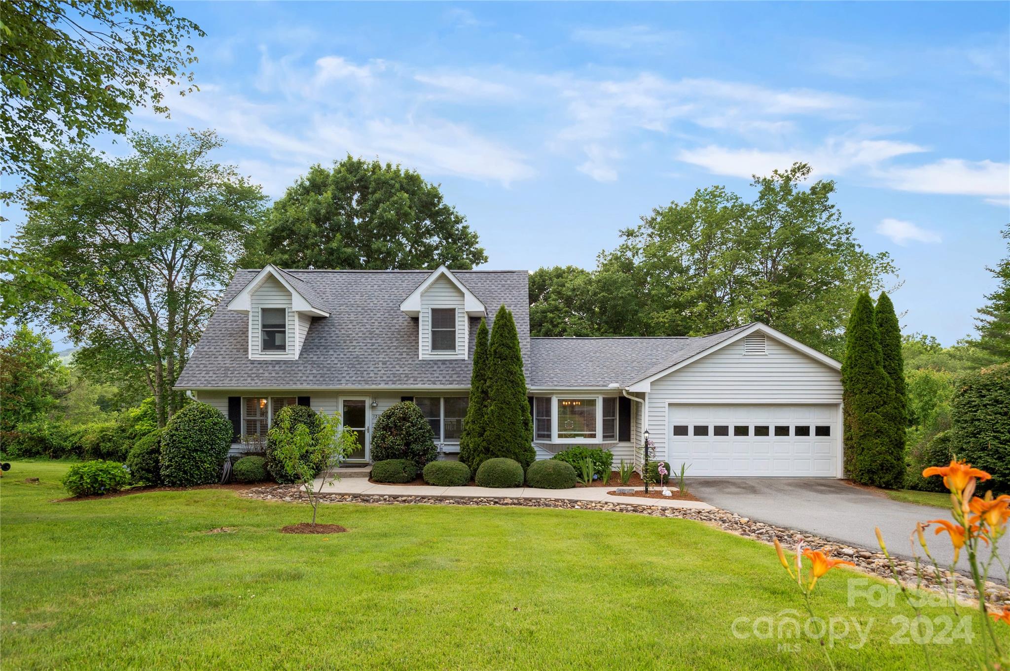 a view of a house with a big yard and large trees