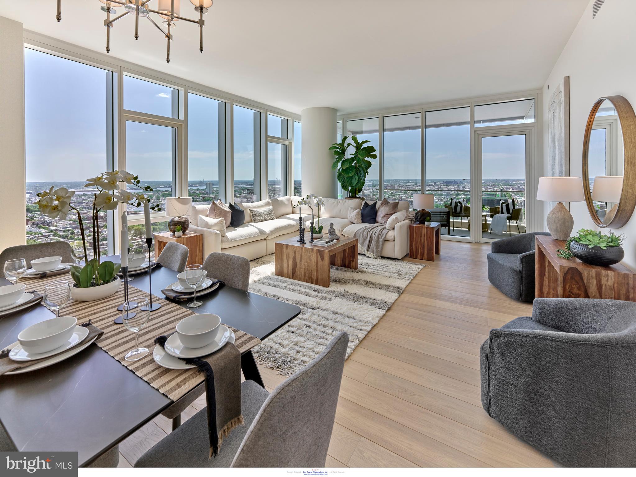 a living room with furniture large windows and wooden floor