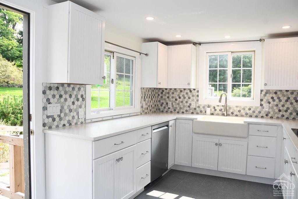 a kitchen with white cabinets and a window