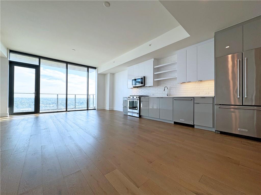 a view of a kitchen with a fridge and wooden floor