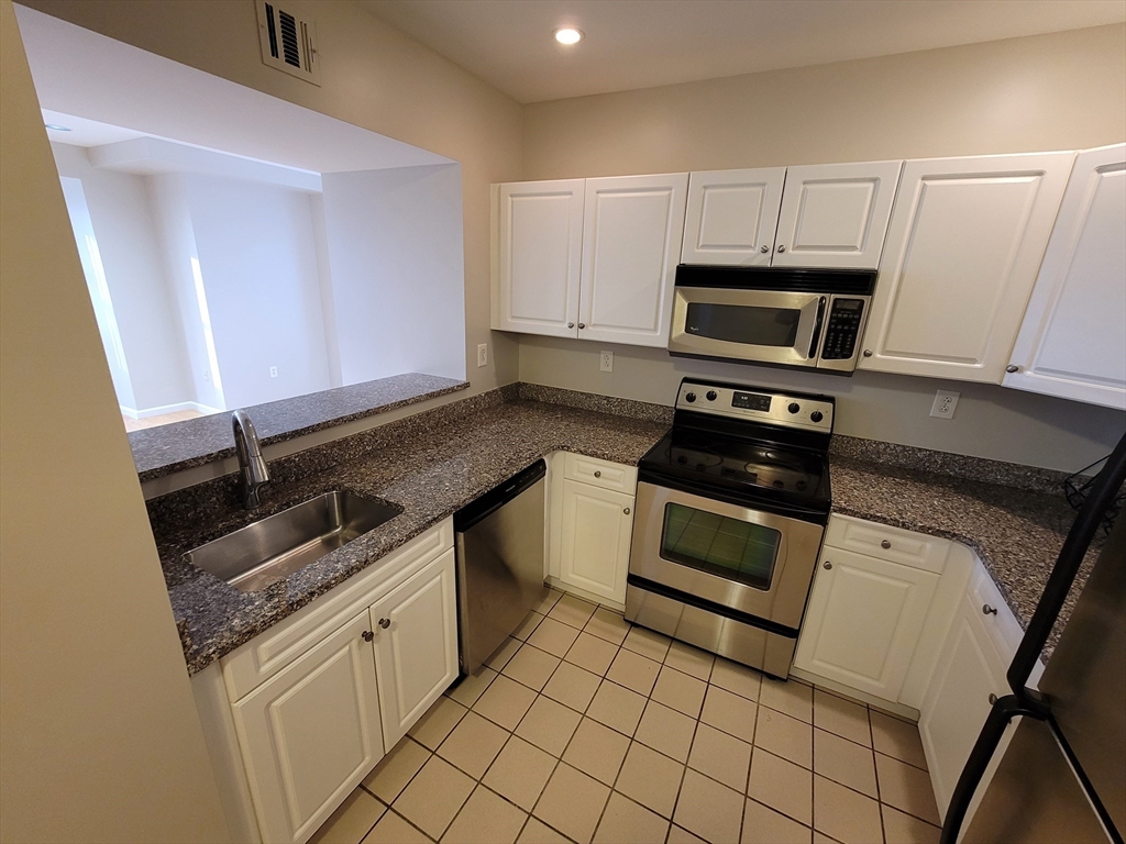 a kitchen with granite countertop a stove sink and cabinets